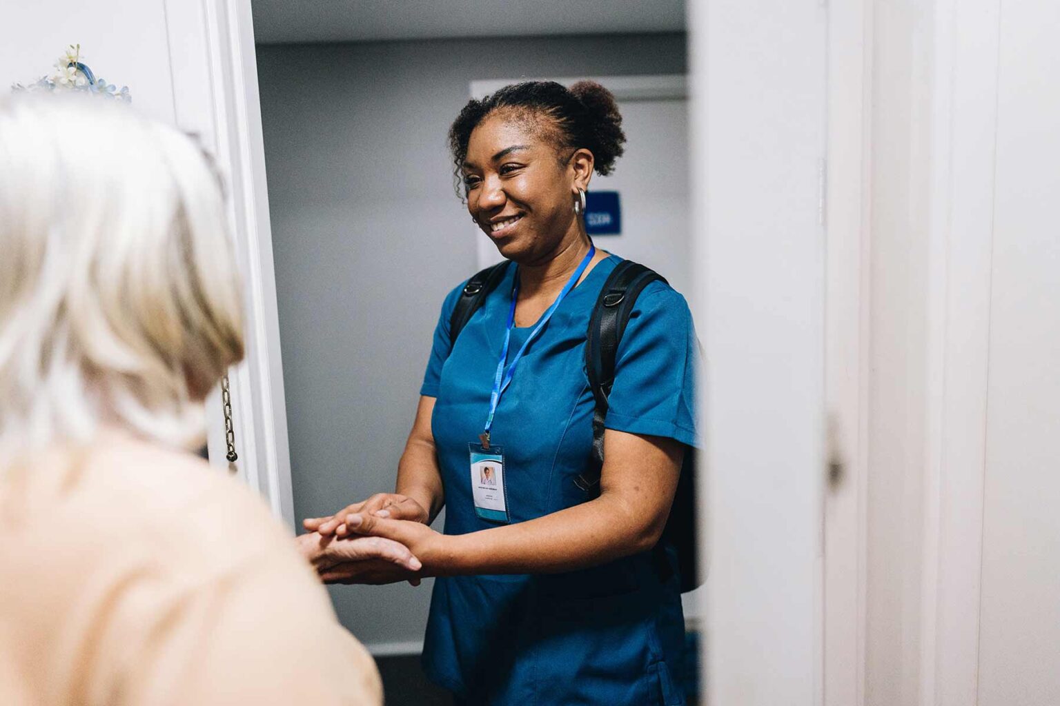 A smiling nurse, holding a patient's hand.